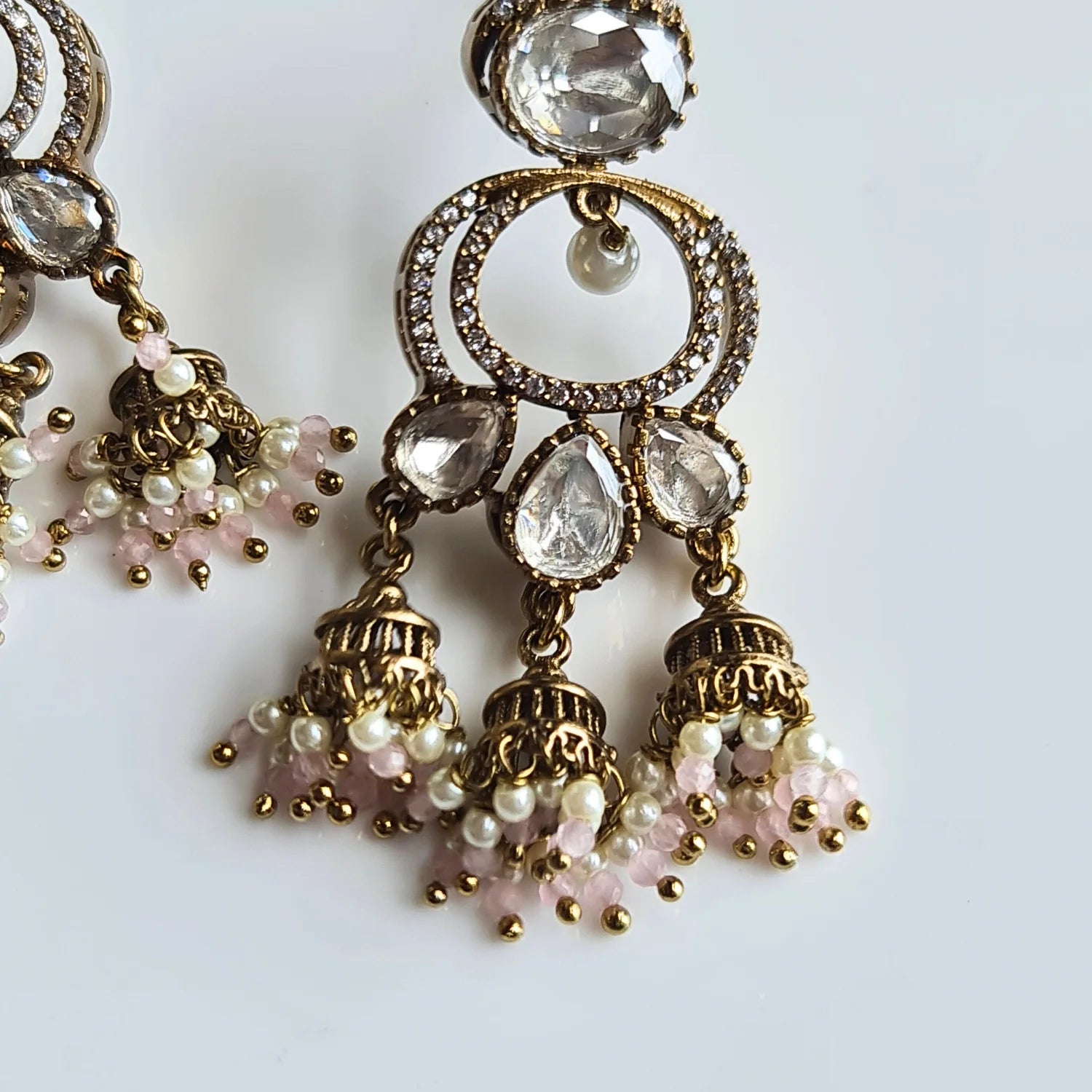 Close-up of ornate Kundan Jhumka earrings with rich pink and white pearl bead drops and a delicate ear chain.

