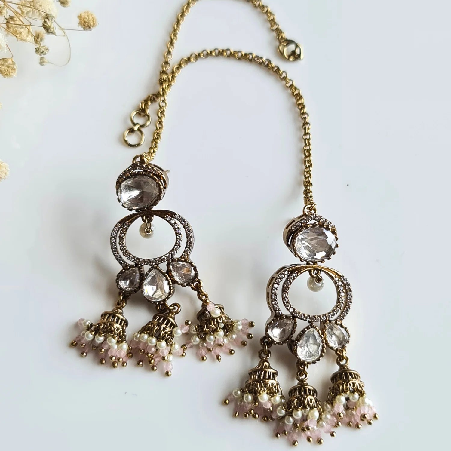 Elegant Kundan Jhumka earrings with delicate light pink pearl bead drops and attached ear chain (kaan chain), on a white surface.

