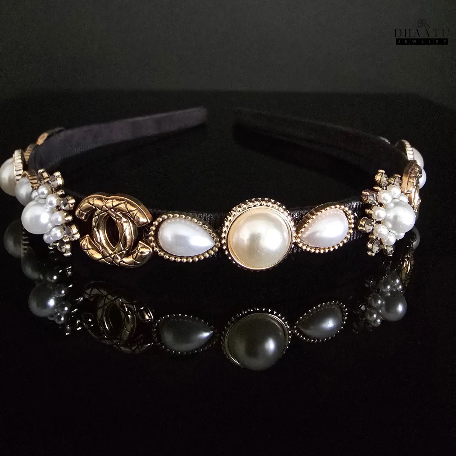 Detailed view of a luxurious artificial headband featuring teardrop and round faux pearls, gold settings, and crystal clusters with a dark reflection.

