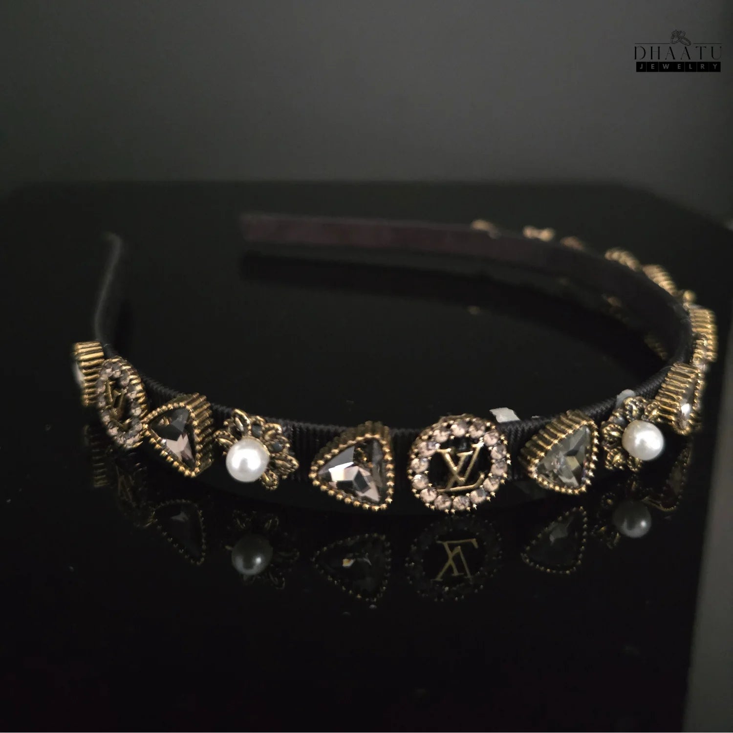 Side view of a modern black hairband featuring intricate gold-toned crystal and faux pearl embellishments.