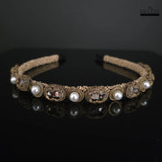 Modern western gold-toned headband featuring pearls and crystals against a dark background for dramatic effect