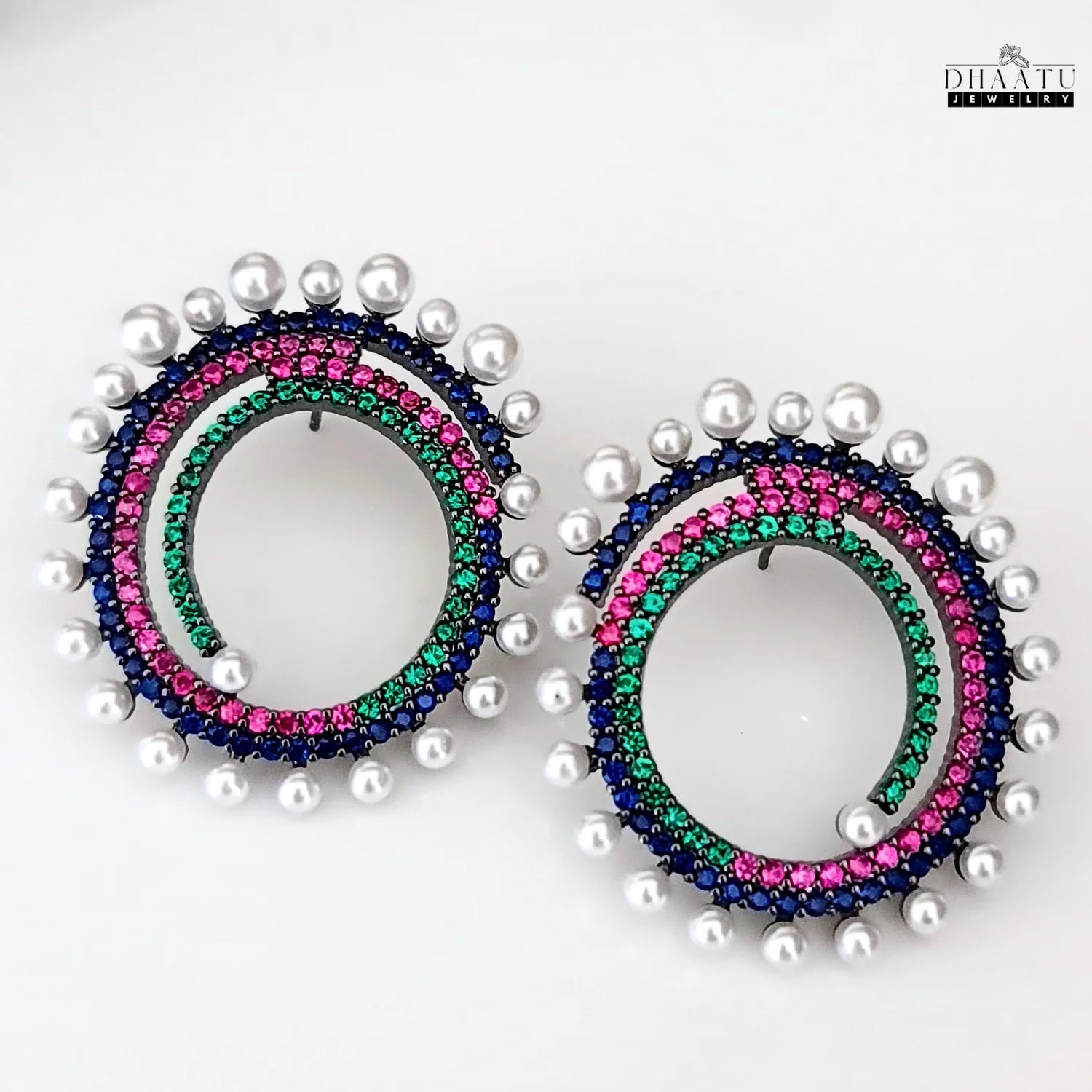 High-resolution image of Dhaatu Jewelry multi-color spiral earrings with pearls, featuring blue, pink, and green stones on a clean white background.