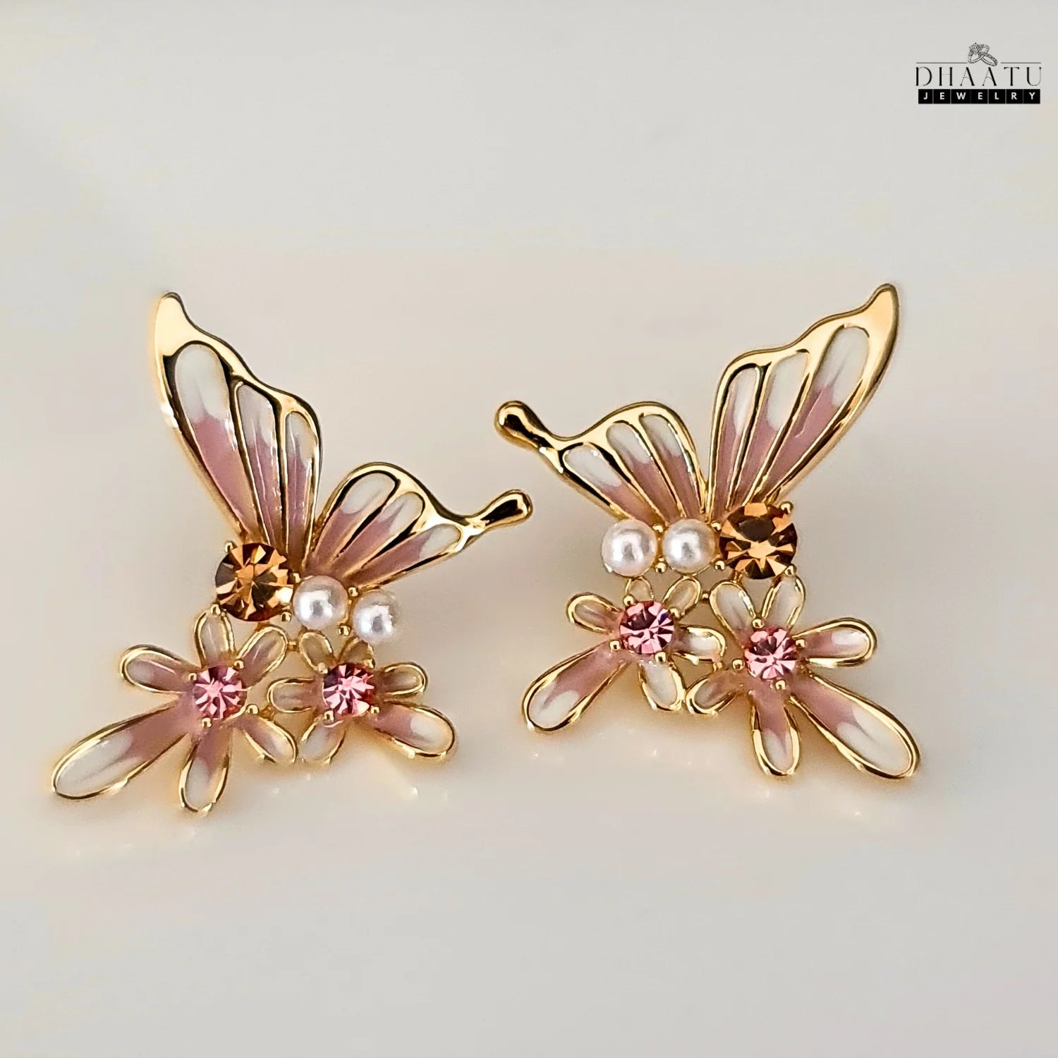Pair of pink and white butterfly and flower stud earrings on a white background.