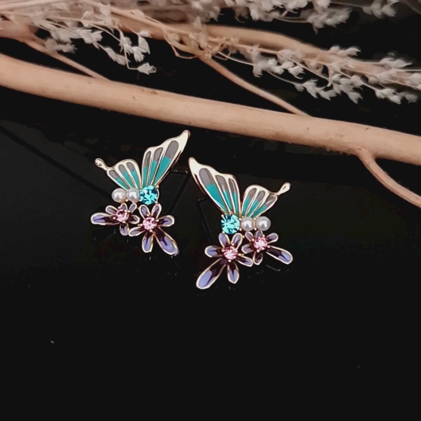 Load video: Video showcasing the turquoise and purple butterfly and flower stud earrings with pearl and crystal details.