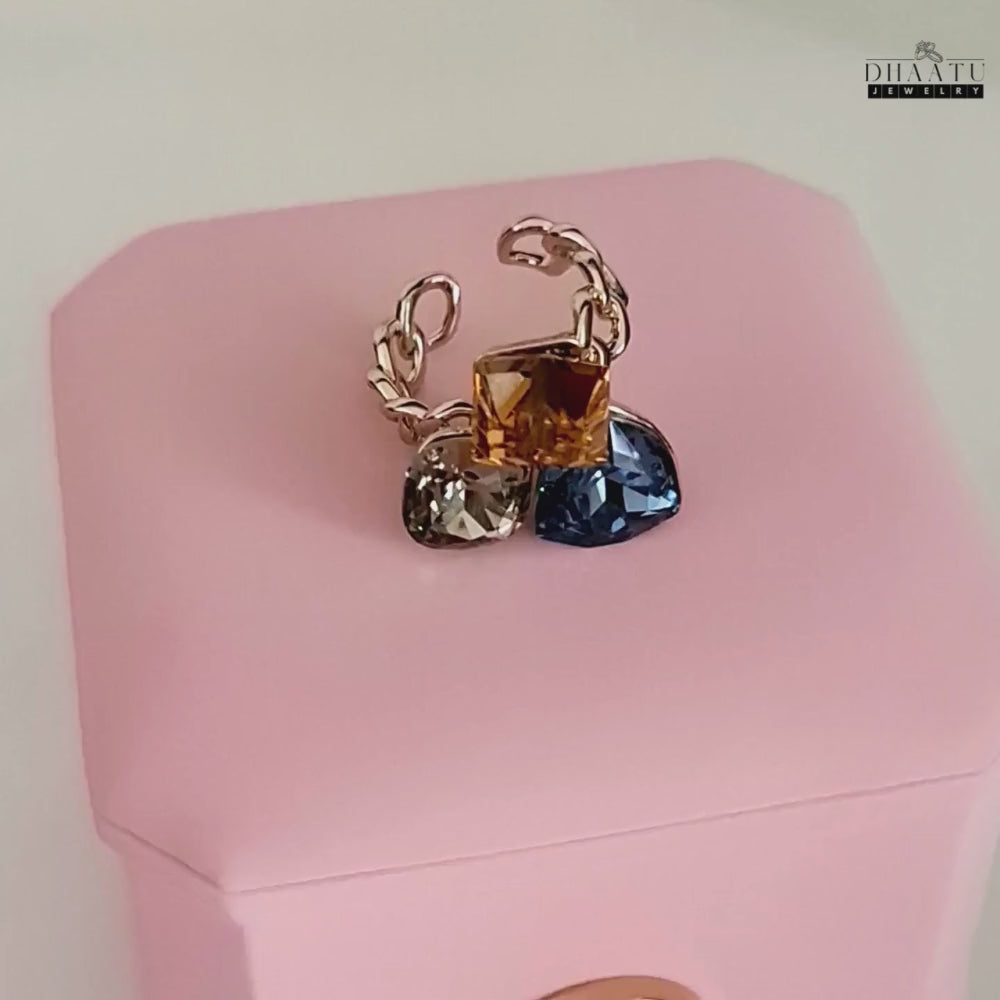 Load video: Video showcasing the multi-colored crystal cocktail ring with rose gold plating, highlighting its intricate chain-link design and sparkling stones.