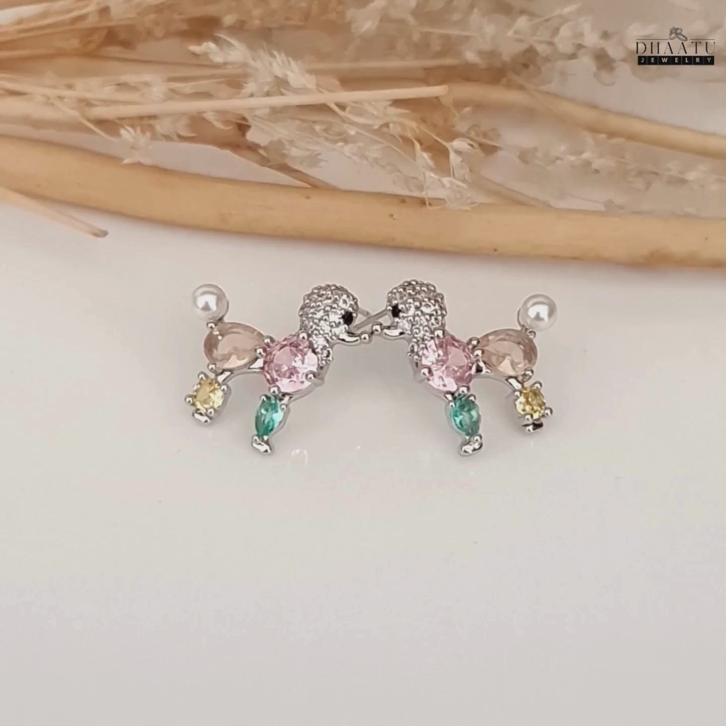 Load video: Video showcasing the pastel-colored poodle earrings with faux pearls and crystals on a white surface.