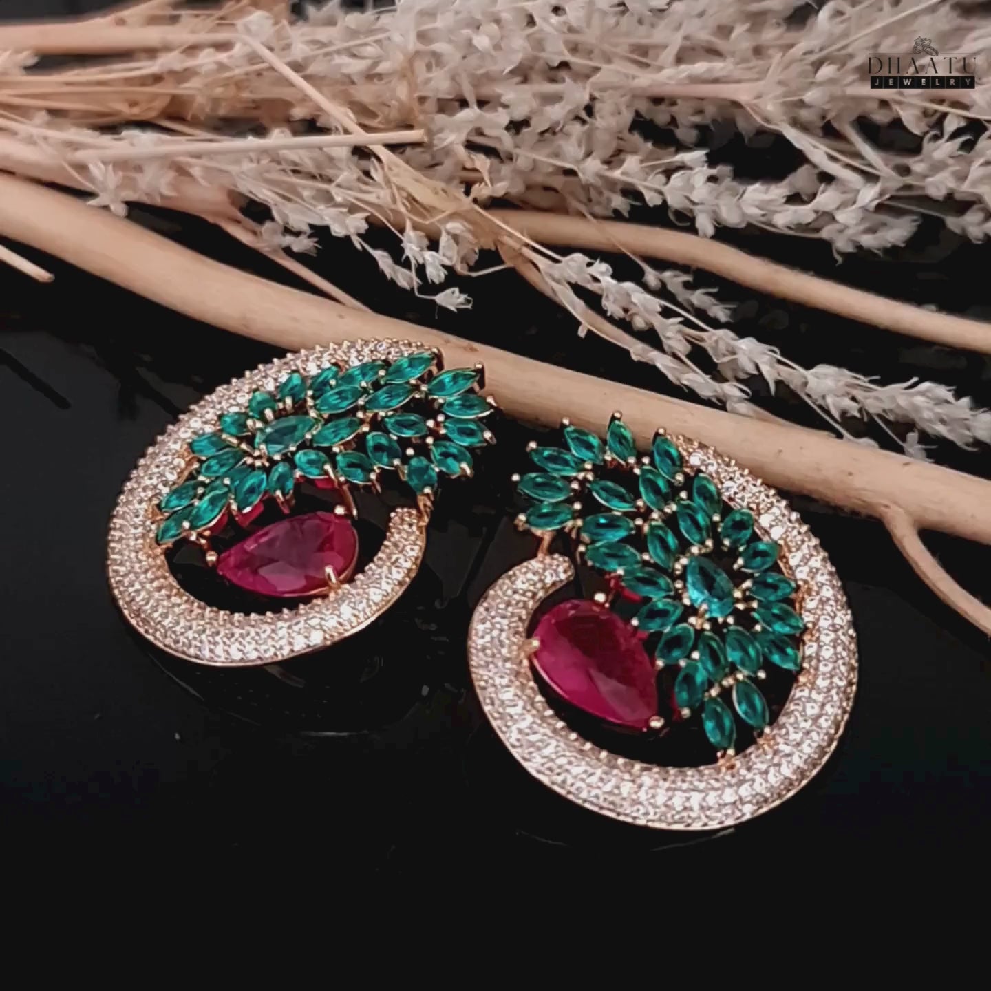 Load video: A video of Dhaatu&#39;s green and ruby CZ stone stud earrings, rotating to show the craftsmanship and how the stones catch the light.