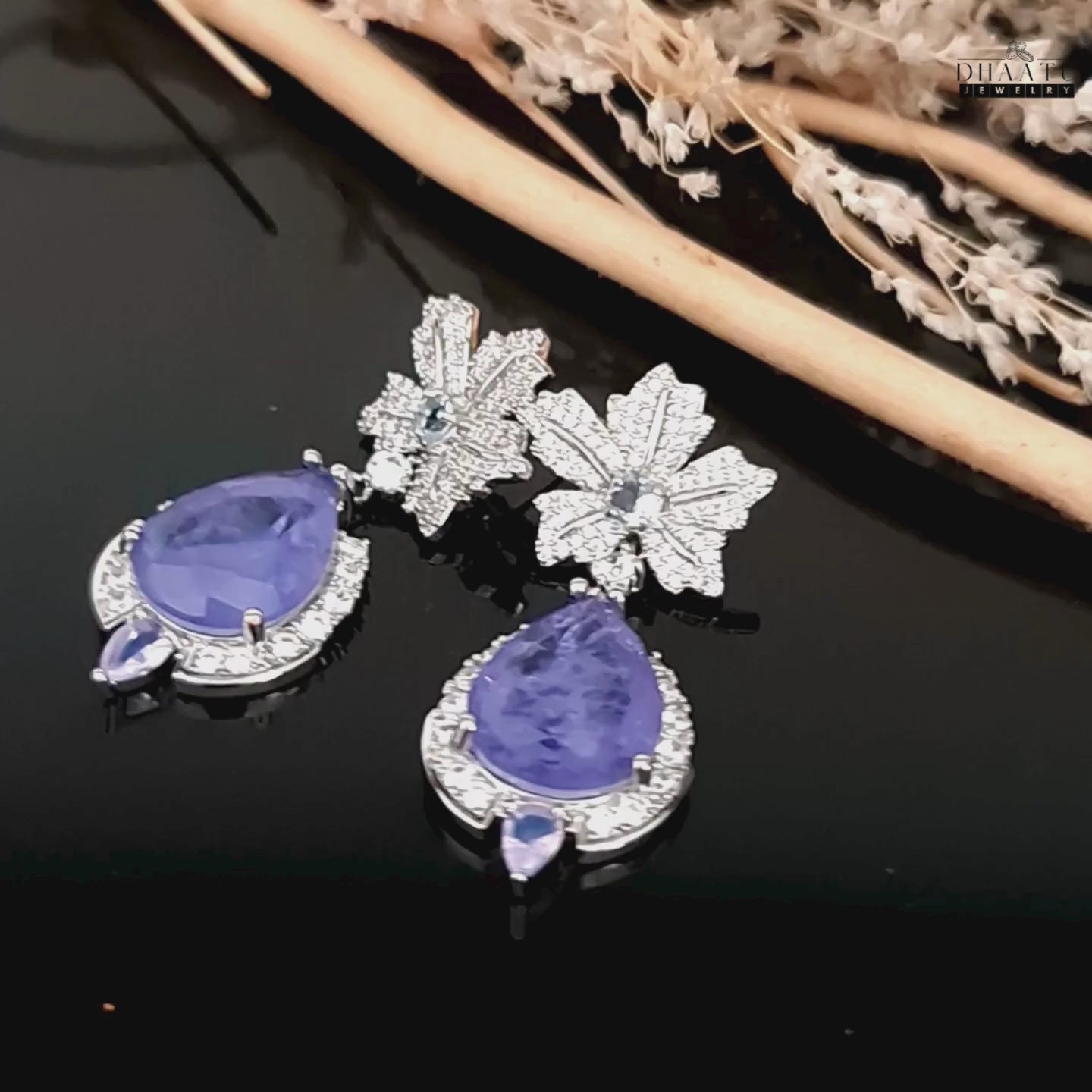 Load video: A video showing the sparkle of tanzanite and cubic zirconia drop earrings on a dark background.