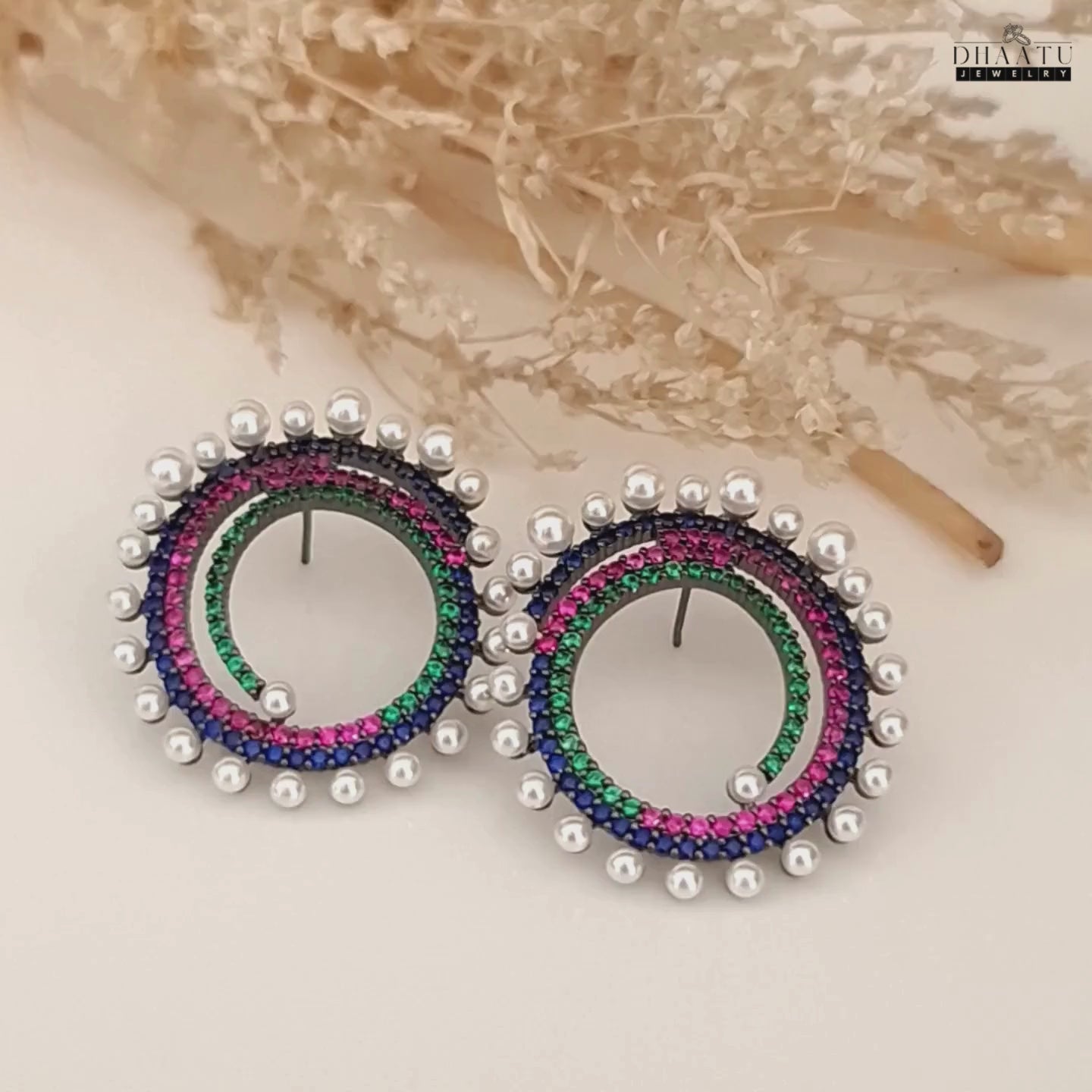 Load video: A short video showcasing the Dhaatu Jewelry multi-color spiral stud earrings from various angles, highlighting the sparkling gemstones and pearls.
