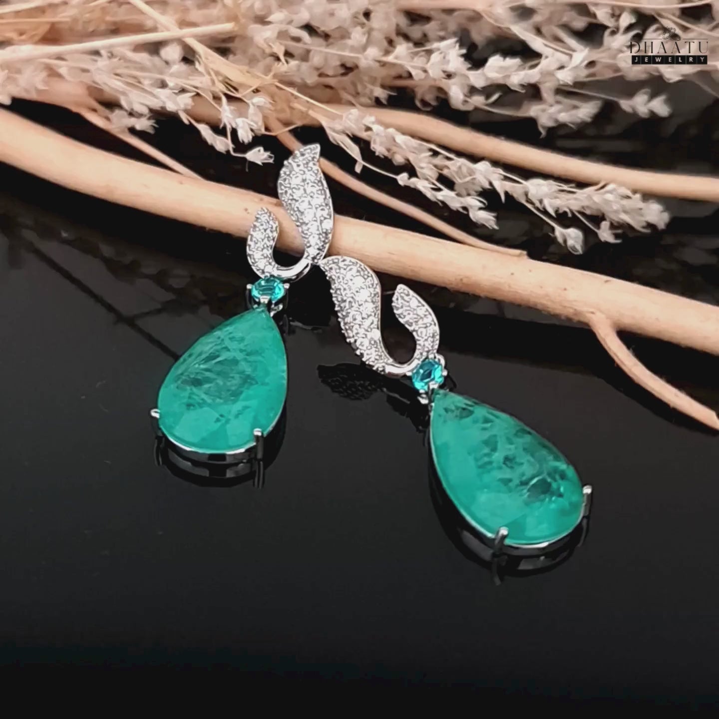 Load video: Video showcasing Dhaatu Jewelry Paraiba green stone dangle earrings with zircon detail, moving to show sparkle and design.

