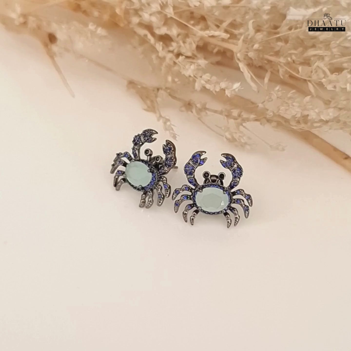 Load video: A video showcasing the silver-toned crab earrings from multiple angles, highlighting the dark blue and aquamarine zircon stones.