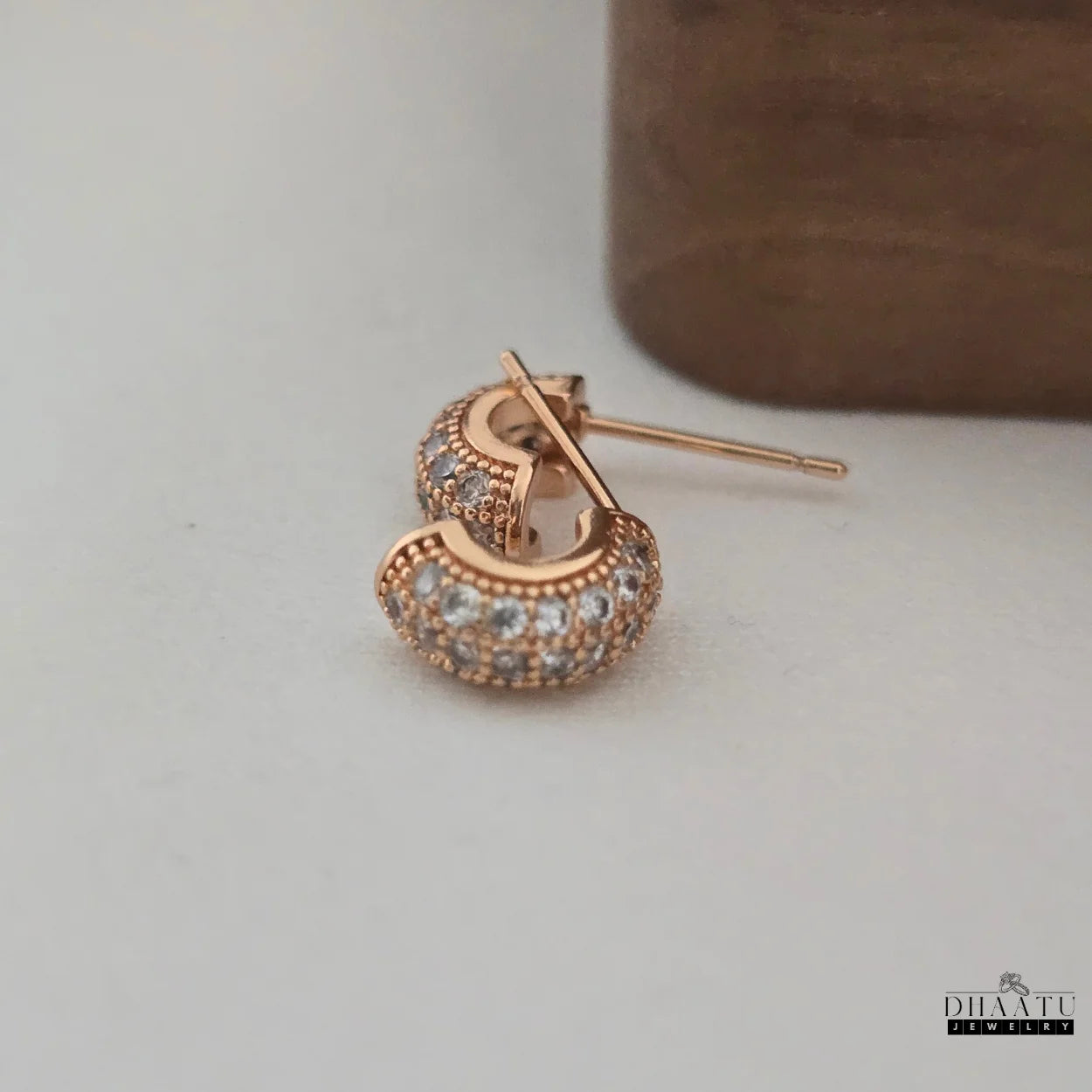 Back view of a single rose gold plated huggie hoop earring with zircon pave, showing the sturdy post and butterfly clasp for secure wear.