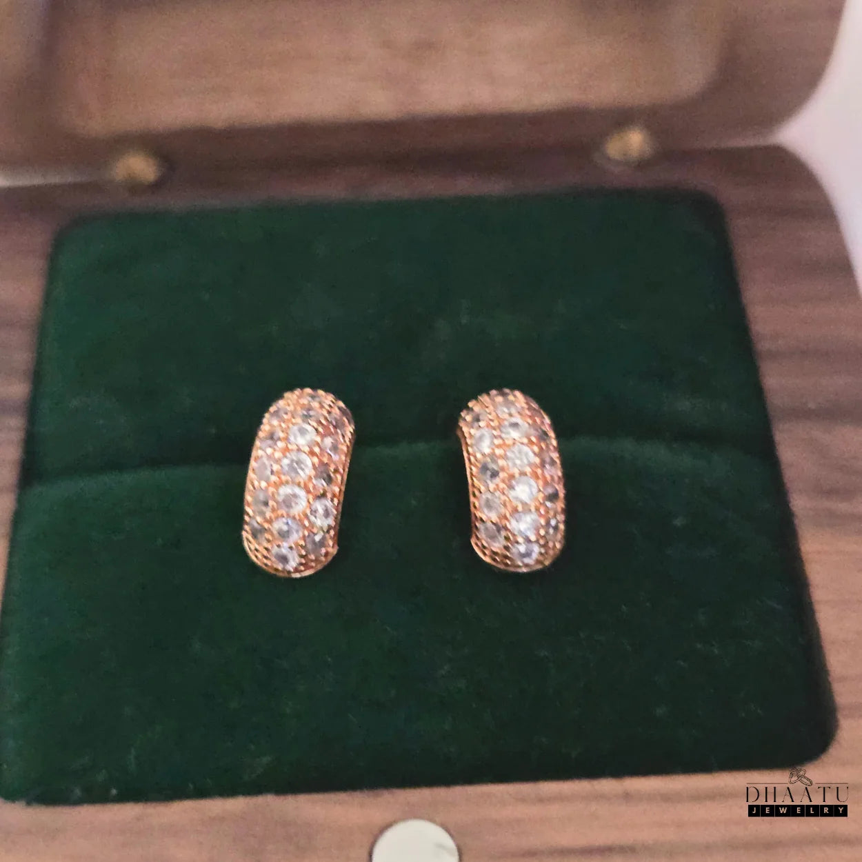 Pair of rose gold plated huggie hoop earrings with zircon pave in a dark green velvet jewelry box, highlighting their secure and luxurious packaging.