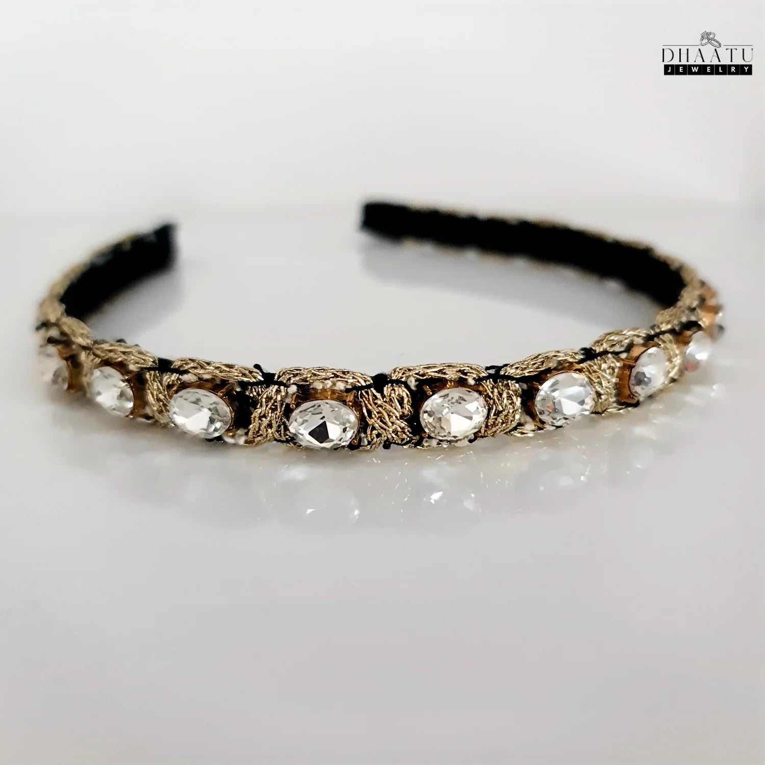 Modern Western headband with clear crystals and golden woven detailing, displayed on a clean white background.

