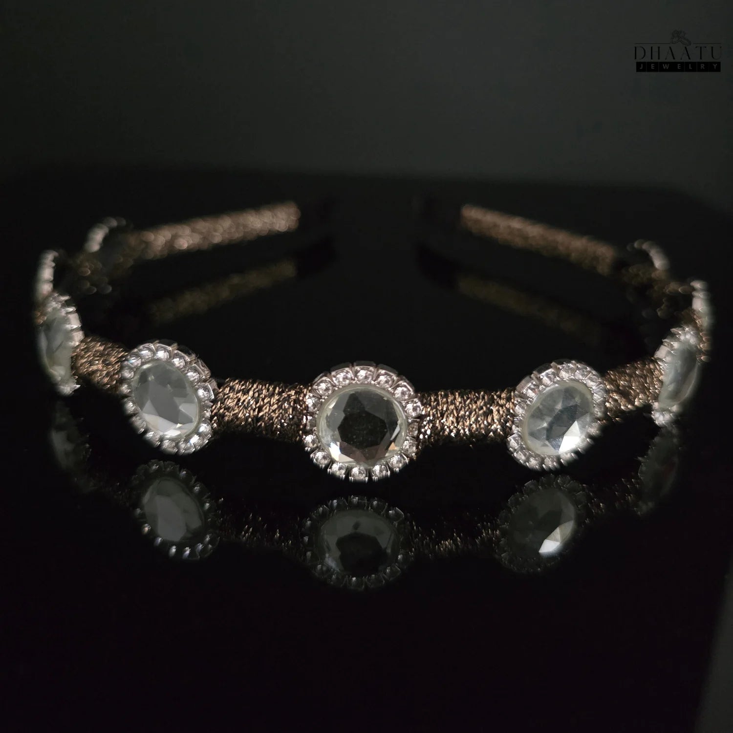 Sparkling crystal embellished hairband with a dark brown braided band against a black background, showcasing the clear crystals