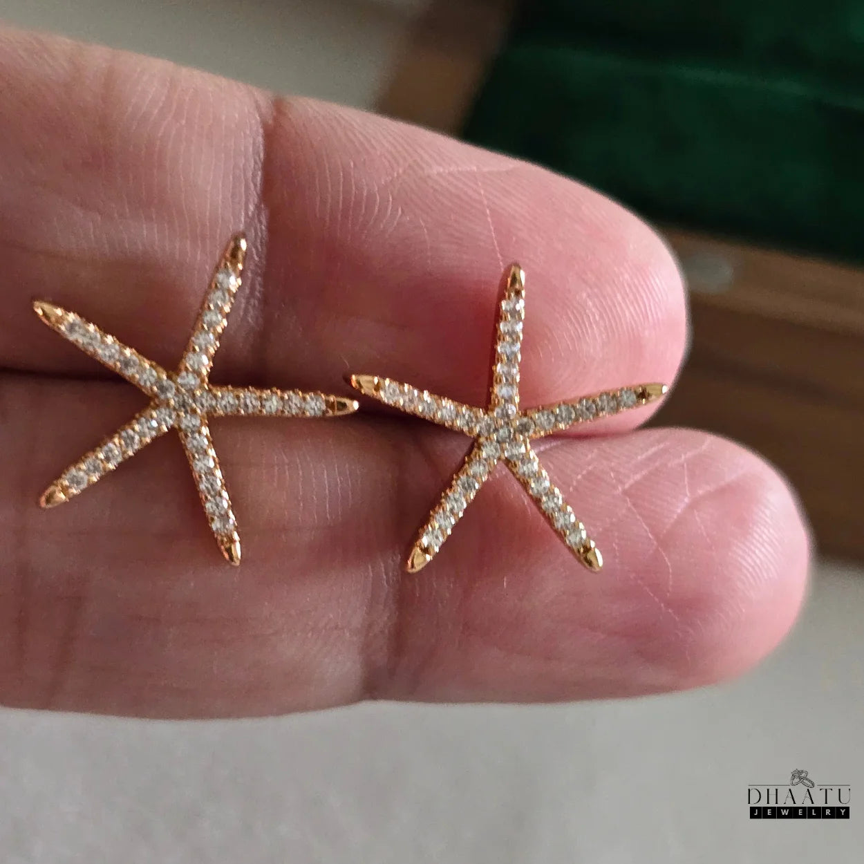 Starfish-shaped earrings with rose gold and clear stones held between fingers.