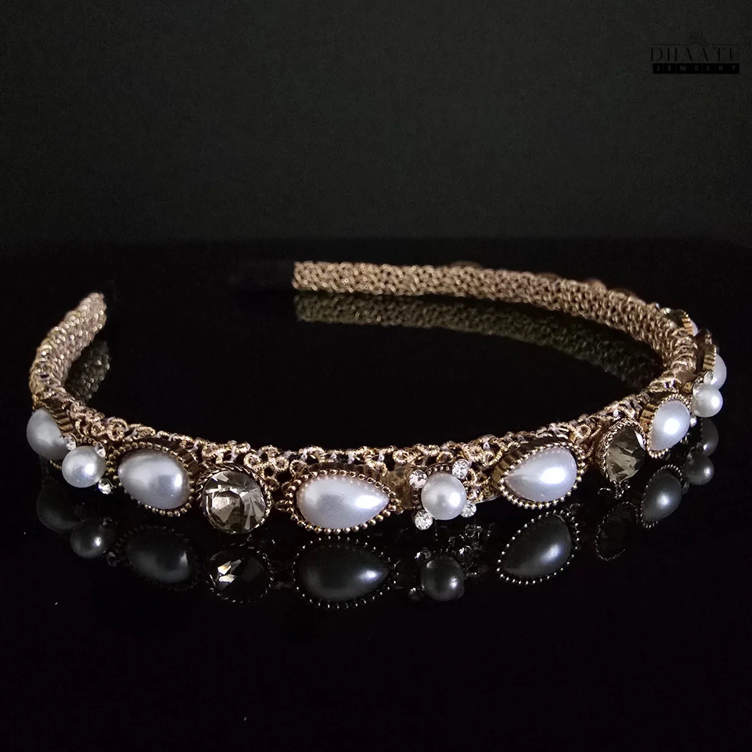 Dhaatu Jewelry gold-tone hairband featuring multiple white pearls and clear crystals, with a clear reflection on a dark surface
