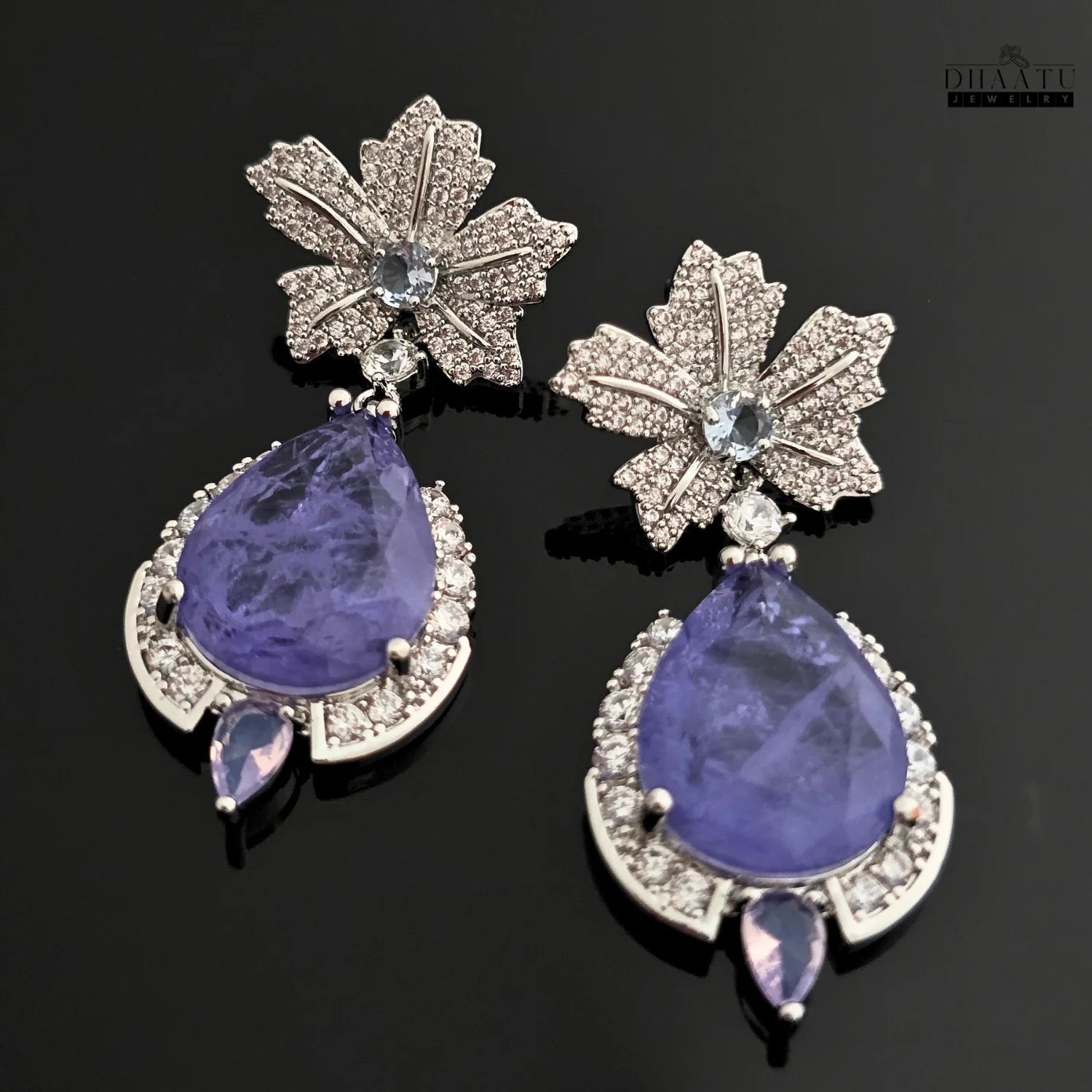 A close-up of the tanzanite drop earrings, highlighting the detailed leaf design and stone settings.