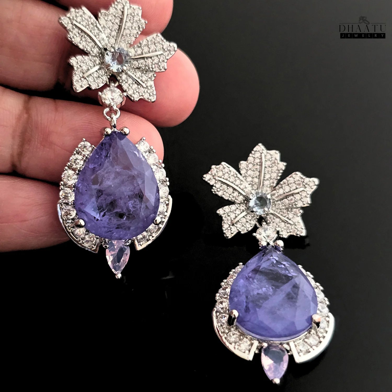 A pair of silver-toned drop earrings featuring a leaf stud with cubic zirconia and a large tanzanite teardrop.