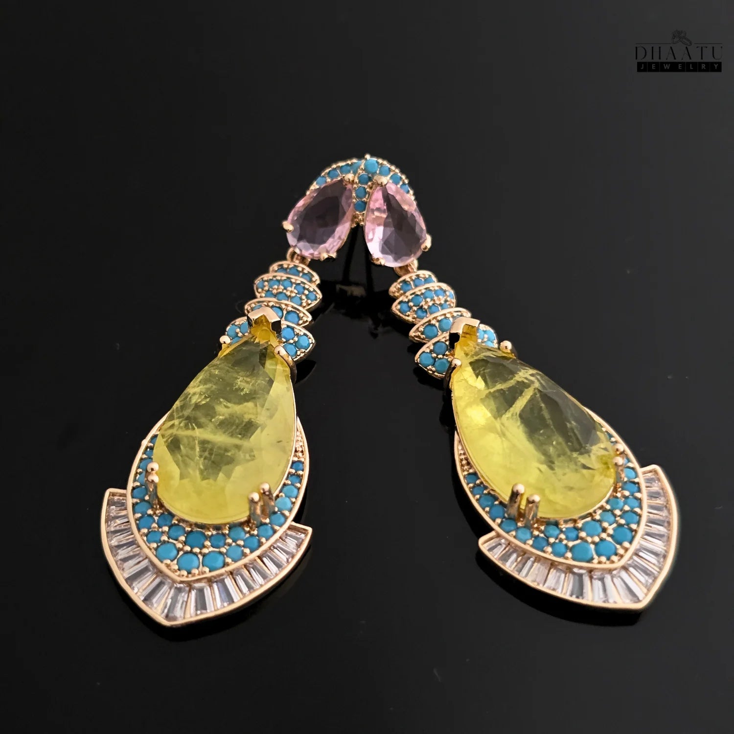 A pair of yellow stone dangle earrings with turquoise and cubic zirconia, shot on a sleek black background for a dramatic effect.